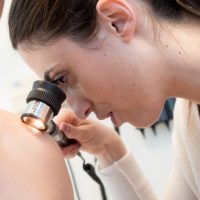 doctor-examining-patients-shoulder-with-a-light-melanoma-skin-cancer-specialist-dermatology-treatment-with-doctor-fakouri-in-texas.jpeg